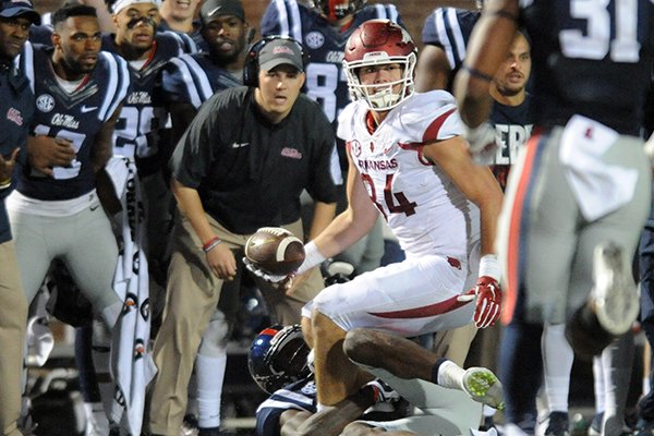 Arkansas tight end Hunter Henry (84), in the grasp of Mississippi defensive back Tony Bridges (1), laterals the ball back to Arkansas running back Alex Collins (3), who runs for a first down on a 4th and 25 play in overtime during an NCAA college football game in Oxford, Miss., on Saturday, Nov 7, 2015. Arkansas won 53-52 in overtime. (Bruce Newman/The Oxford Eagle via AP)