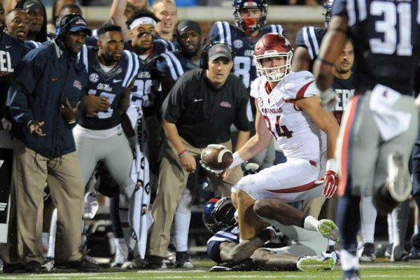 Arkansas tight end Hunter Henry (84), in the grasp of Mississippi defensive back Tony Bridges (1), laterals the ball back to Arkansas running back Alex Collins (3), who runs for a first down on a 4th and 25 play in overtime during an NCAA college football game in Oxford, Miss., on Saturday, Nov 7, 2015. Arkansas won 53-52 in overtime. (Bruce Newman/The Oxford Eagle via AP)