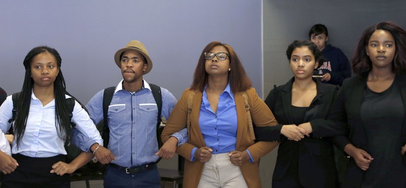 In this Saturday, Nov. 7, 2015, photo, members of the Concerned Student 1950 and the Legion of Black Collegians link arms during a protest in Mark Twain Dining Hall the University of Missouri campus, in Columbia, Mo. Some campus groups have been protesting the way university president Tim Wolfe has dealt with issues of racial harassment during the school year. Jonathan Butler, a black graduate student, is on a hunger strike to call attention to the issue. Missouri football players announced Saturday night on Twitter that they will not participate in team activities until the university president is removed from office. 