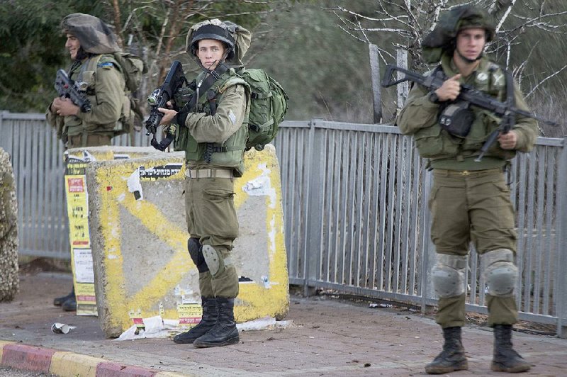 Israeli soldiers stand guard Sunday at a bus stop near Nablus in the West Bank after a Palestinian man rammed his vehicle into a group of Israelis, injuring four. The Palestinian was shot and killed.