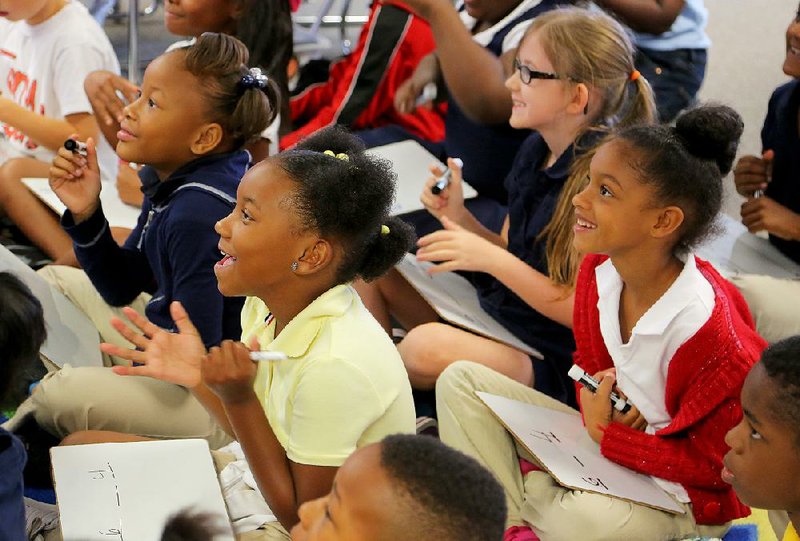 Terry Elementary second-graders Renia James (from left), Amaya Hillery, Olivia Jackson and Allyssa Patterson celebrate a victory in a math game against their teacher, Aimee Freeman, on a recent day at the Little Rock school.