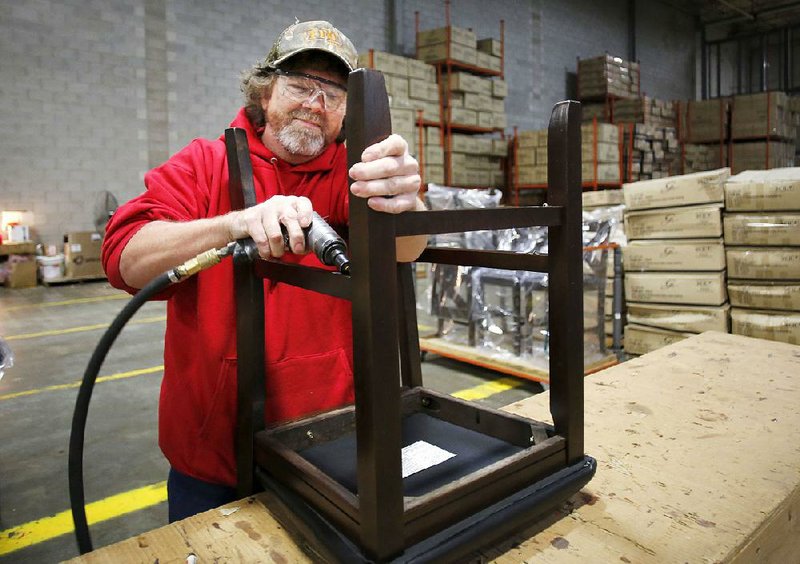 Mark Rudick assembles a chair Monday at FFO Home’s new corporate headquarters in Fort Smith. The company moved its corporate offices from Muldrow, Okla., into a portion of the former Whirlpool Corp.’s distribution center this year.