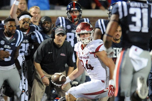 Arkansas tight end Hunter Henry (84), in the grasp of Mississippi defensive back Tony Bridges (1), laterals the ball back to Arkansas running back Alex Collins (3), who runs for a first down on a 4th and 25 play in overtime during an NCAA college football game in Oxford, Miss., on Saturday, Nov 7, 2015. Arkansas won 53-52 in overtime. (Bruce Newman/The Oxford Eagle via AP)