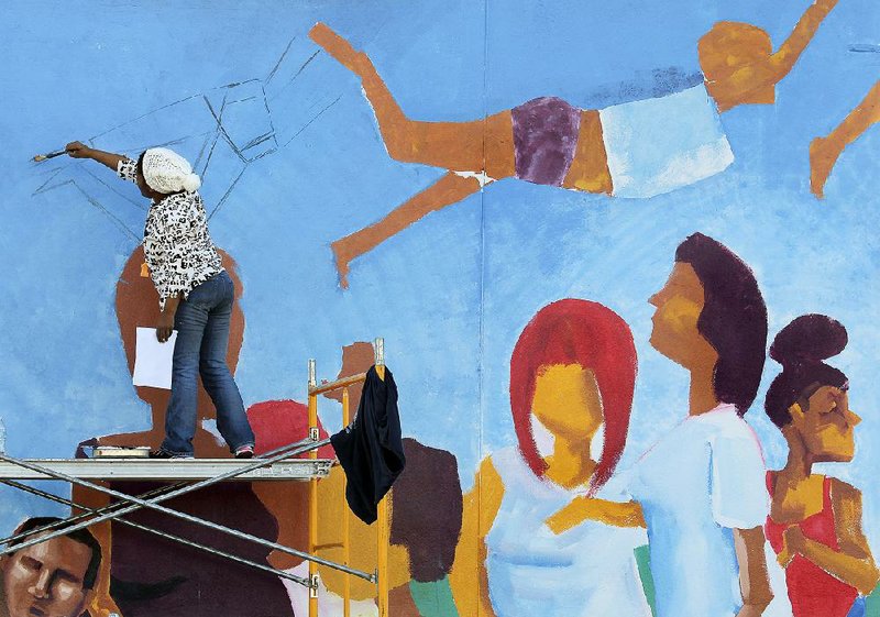 Angela Davis Johnson, an Atlanta artist formerly from Arkansas, works on a mural at Fourth and Poplar streets in North Little Rock’s Argenta district on Tuesday.