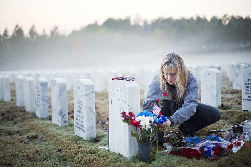 Jiffy Helton Sarver of Monroe, Ga., puts flowers at the grave of her son, 1st Lt. Joseph Helton Jr., at sunrise Wednesday at Georgia National Cemetery in Canton. Helton was killed in Iraq in 2009. “This was his favorite time of day,” Sarver said. “He loved sunrises.” 