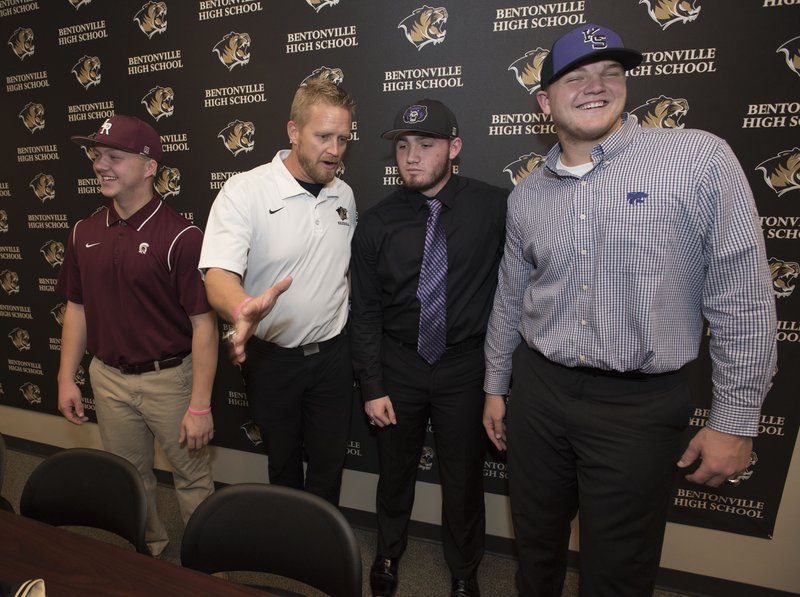 NWA Democrat-Gazette/J.T. WAMPLER Bentonville baseball players Kasey Ford (from right), Drew Young and Carter Brown (left) visit with coach Todd Abbott (second from left) Wednesday after signing letters of intent to play college baseball. Ford signed with Kansas State University, Young signed with the University of Central Arkansas and Brown signed with Arkansas-Little Rock.