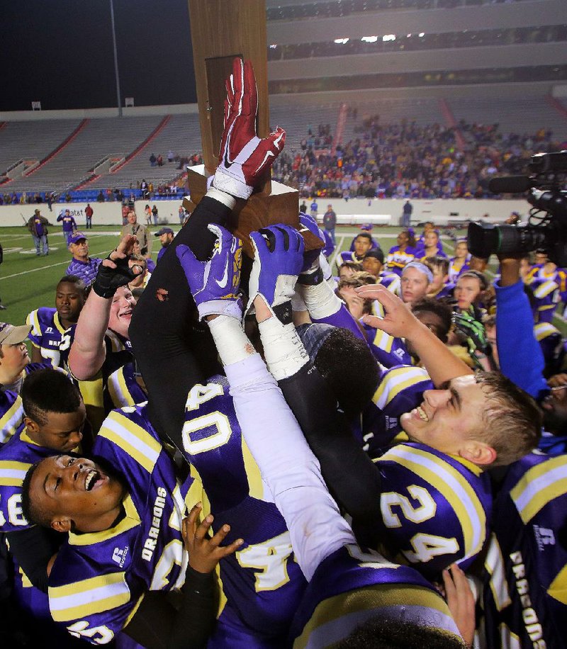 Junction City players hoist the championship trophy after they beat Hazen 38-6 to win the Class 2A state title last season at War Memorial Stadium in Little Rock. The Dragons, who fi nished the regular season 6-2 and host Johnson County Westside tonight in the opening round of the Class 2A playoffs, have won three consecutive championships and are looking to become the fi rst team to win four in a row since Barton did it from 1986-1989.