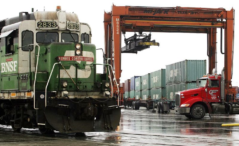 A BNSF RAILWAY locomotive moves past a loading crane and stacked shipping containers as it makes its way through the railroad’s freight intermodal facility in Elwood, Ill., in this file photo. 