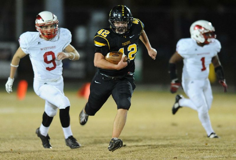 Prairie Grove running back Cole Walker (42) runs past Jonesboro Westside’s Demarius Smith during the first round of the Class 4A state playoffs Friday. The Tigers won their 10th consecutive game and will take on Ashdown next week in the second round. For more photos from the game, visit nwadg.com/photos.