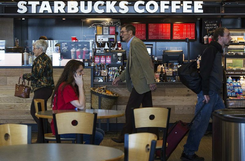 Travelers pass the Starbucks Coffee stand near the baggage claim area Friday at Bill and Hillary Clinton National Airport/Adams Field. Concessions are a vital part of airport revenue.