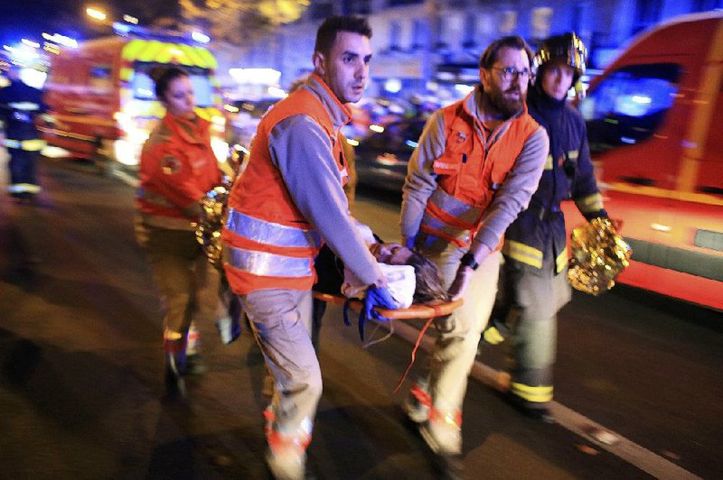 Rescuers rush a woman out of the Bataclan concert hall after security forces carried out an assault Friday night on attackers holding scores of people hostage inside.