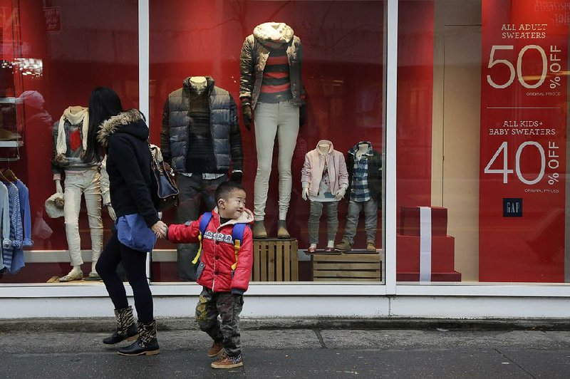 A mother and son pass a window advertising discount prices at a Gap store Thursday in Brooklyn, N.Y. Sales at U.S. retailers rose less than forecast in October.