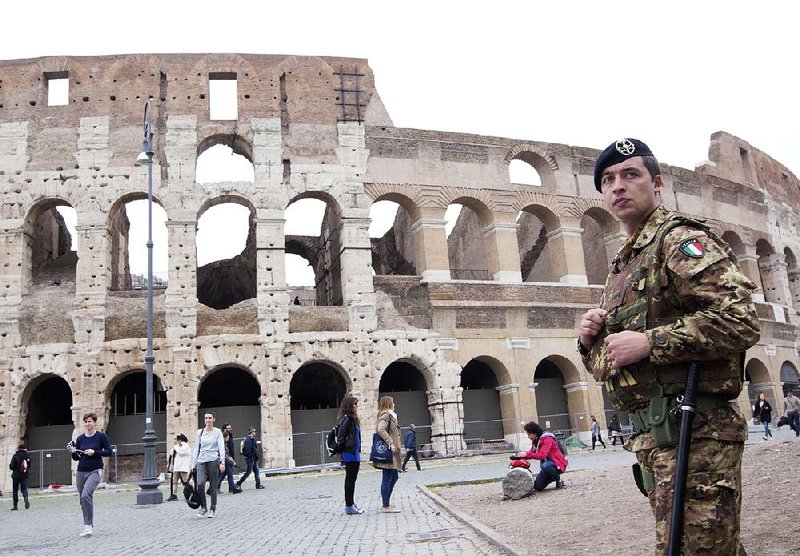 An Italian soldier patrols Saturday outside the Colosseum in Rome. Officials announced heightened security inside Italy and along its borders, especially with France. 