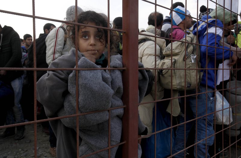 People wait at the entrance of the transit center for refugees Saturday near the southern Macedonian town of Gevgelija, after crossing the border from Greece. 