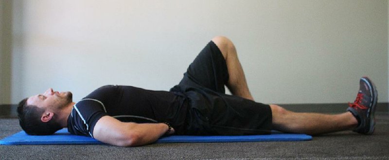 Josh Holt, fitness director at Little Rock Racquet Club, does the first step of the Lumbar Situp exercise 