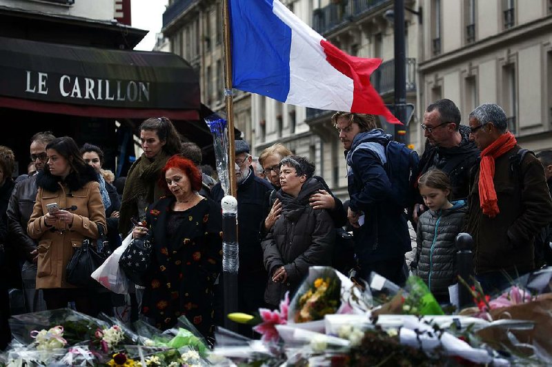 People gather Monday in front of Le Carillon cafe, one of the sites of the recent attacks in Paris. French President Francois Hollande says the Paris attacks targeted “youth in all its diversity” and that the victims were of 19 different nationalities.