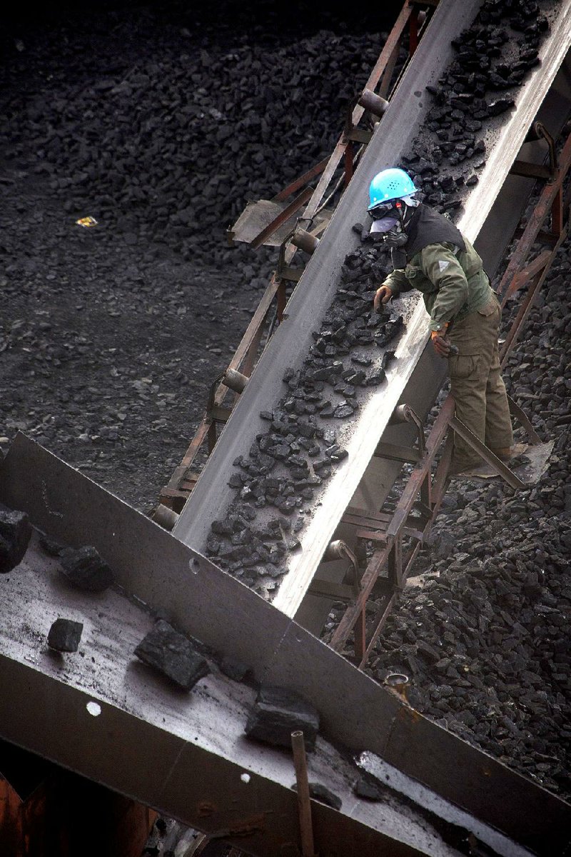 A worker monitors coal carried on a conveyor belt at a mine near Ordos in China’s Inner Mongolia Autonomous Region on Nov. 4. China burns 4 billion tons of coal a year, four times as much as the United States.
