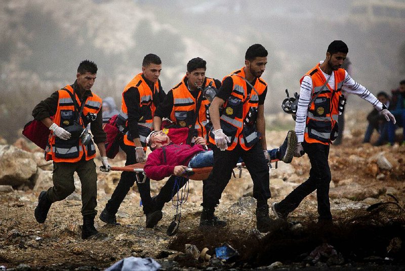 Palestinians carry an injured man during clashes with Israeli troops Monday after the funerals of Ahmad Abu al-Aish and Laith Manasra in the West Bank city of Ramallah. Two Palestinians were killed and three wounded Monday, a health official said.