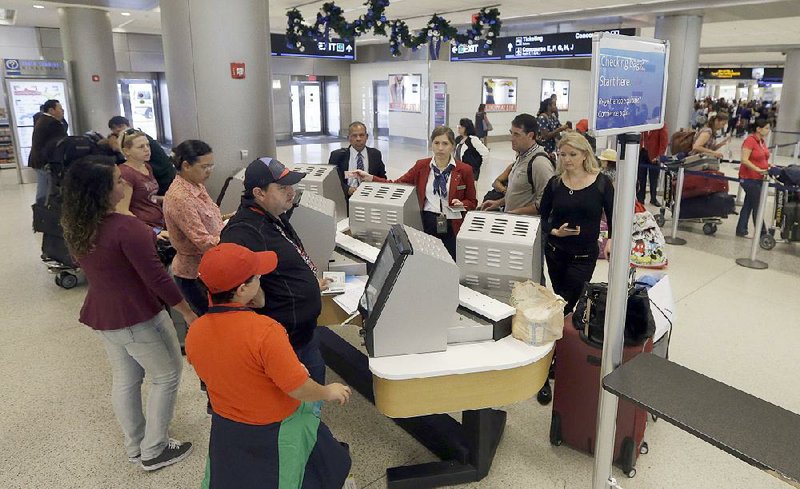 Travelers check in for flights at Miami International Airport in this file photo. A new report said U.S. airlines will collect $18.1 billion in 2015 from fees and other ancillary revenue. 