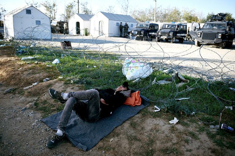A migrant takes a rest Thursday as Macedonian police guard the border near the village of Idomeni in northern Greece. 