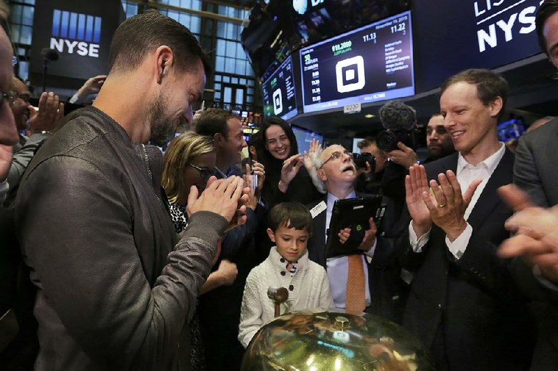 Mac Riley (center), son of Square CFO Sarah Friar, rings a ceremonial bell Thursday to mark the start of trading of shares of Square on the floor of the New York Stock Exchange. The shares rose $4.07 to close at $13.07.
