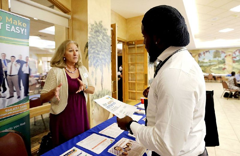 A job seeker (right) talks with a veterans outreach representative for Career Source Broward about opportunities at a job fair for veterans in Pembroke Pines, Fla., in October.