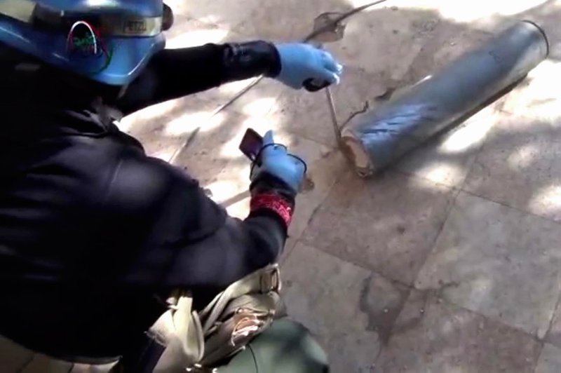 In this August 26, 2013, file image taken from amateur video posted online, appears to show a presumed UN staff member measuring and photographing a canister in the suburb of Moadamiyeh in Damascus, Syria. The Islamic State group is aggressively pursuing development of chemical weapons, setting up a branch dedicated to research and experiments with the help of scientists from Iraq, Syria and elsewhere in the region, according to Iraqi and U.S. intelligence officials.