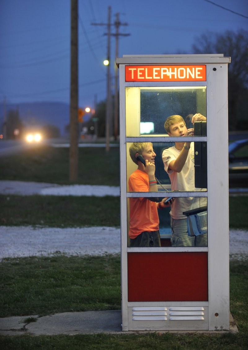 Prairie Grove teenagers Mason McCourt (left) and Blake Williams use the telephone booth on U.S. 62 in Prairie Grove in April, when the booth was first nominated to the National Register of Historic Places. 