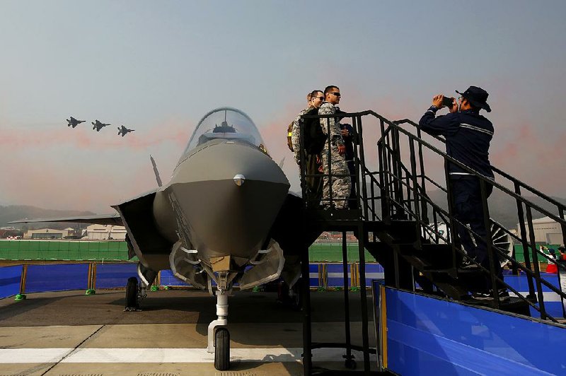 Visitors pose with a Lockheed Martin F-35 Lightning II fighter jet as South Korean air force pilots maneuver F-16K fighters, built by Boeing, during an aerospace exhibition in October in Seongnam, South Korea. 