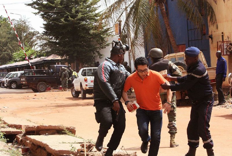 Malian soldiers assist a survivor as he flees the Radisson Blu hotel after Friday’s attack in Bamako, Mali. At least 20 people were killed.