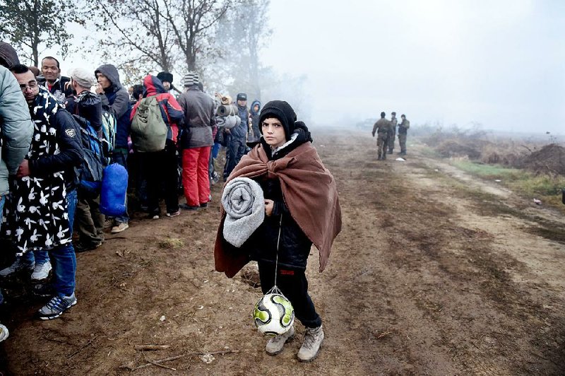A boy waits Friday with other migrants to pass from the northern Greek village of Idomeni to southern Macedonia. 