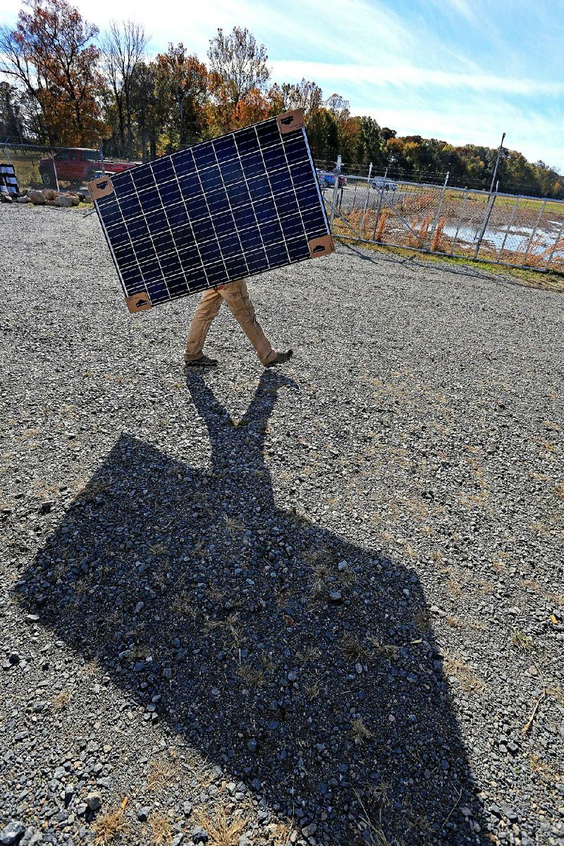 Joe Rice carries a 265-watt solar panel for use during a ceremony Friday at the Bearskin Solar Center community solar power garden in Scott, where people can purchase the solar panels.