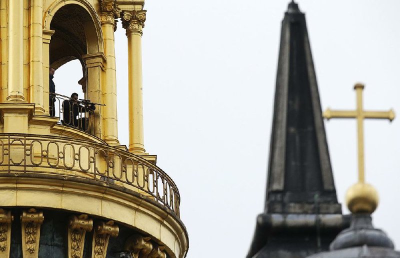A sniper takes position Thursday in the dome of the Hotel National des Invalides in Paris as French President Francois Hollande attended a military ceremony. The information private companies can pass along to authorities in France and Belgium to help in the investigation of the Paris terrorist attacks is limited because of stricter European privacy laws. 
