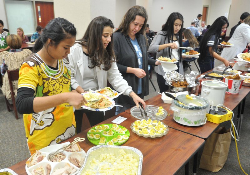 Risa John (from left), student, Angie Caster, nurse, Sarah Edgar, English teacher, Ana Martinez and Yesenia Ramirez (students) pick out their food Friday during Har-Ber High School’s Language Academy’s annual Thanksgiving Feast. Each of the 63 students in the academy bring a traditional dish from their native country to share with others.