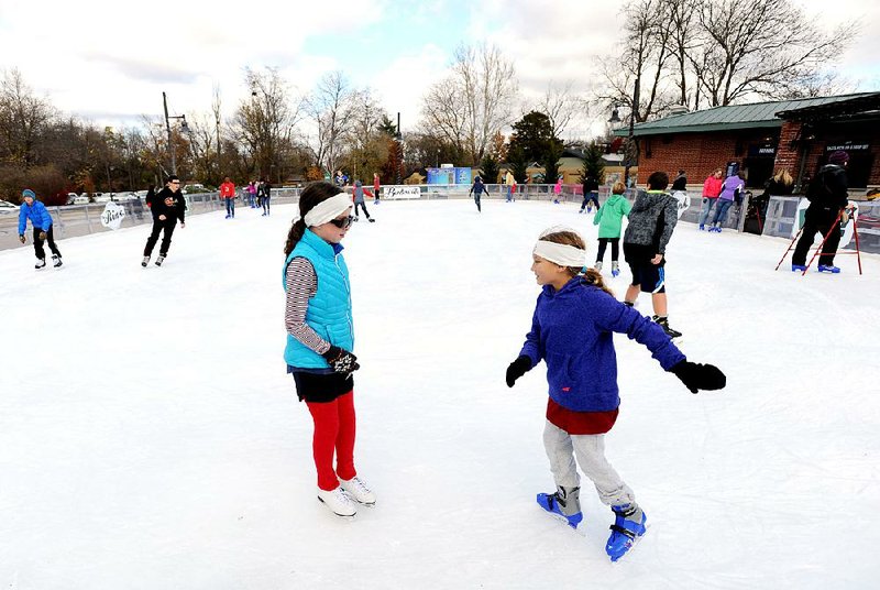 Friends Kate Chrisco (left), 10, and Elliot Halford, 9, both of Bentonville, on Saturday take in the first day of skating at The Rink at Lawrence Plaza in Bentonville. 