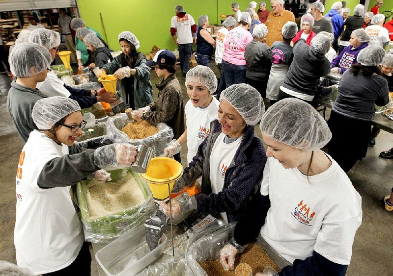 Erica Hendrix (left) and other volunteers across the table from her — Summer Coker (from left), Macie Hendrix and Lauren Lovelady — package food Saturday at the Arkansas Rice Depot in Little Rock. The girls are from the youth group at First United Methodist Church of Hot Springs. 