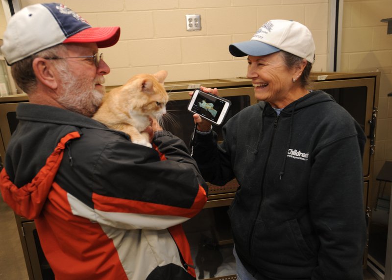 Charles and Lois Harvey of Benton County show Andy, a 6-yearold cat they were in the process of adopting Wednesday, a photograph of their cat, Smudge, with whom Andy is going to share their home at Springdale Animal Services. The animal shelter has reduced its euthanasia rate by 30 percent.