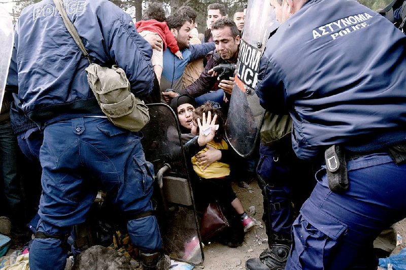 A woman tries to protect her daughter as migrants scuffle with Greek police to reach the border with Macedonia near the Greek village of Idomeni on Sunday. Migrants gathered in Idomeni for a fourth day after being turned away from the border.