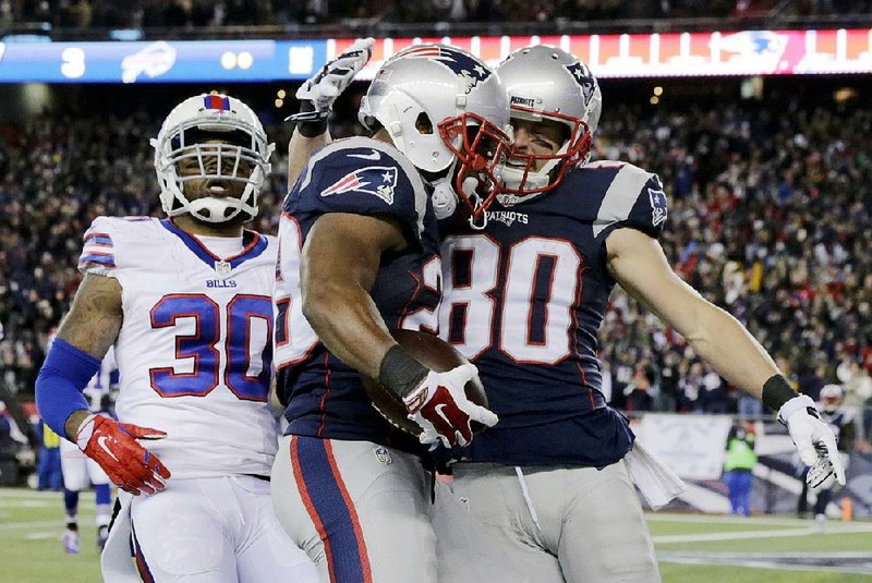 New England Patriots running back James White (center) celebrates with wide receiver Danny Amendola (80) after scoring a touchdown in front of Buffalo Bills safety Bacarri Rambo (30) during the first half of Monday’s game in Foxborough, Mass.
