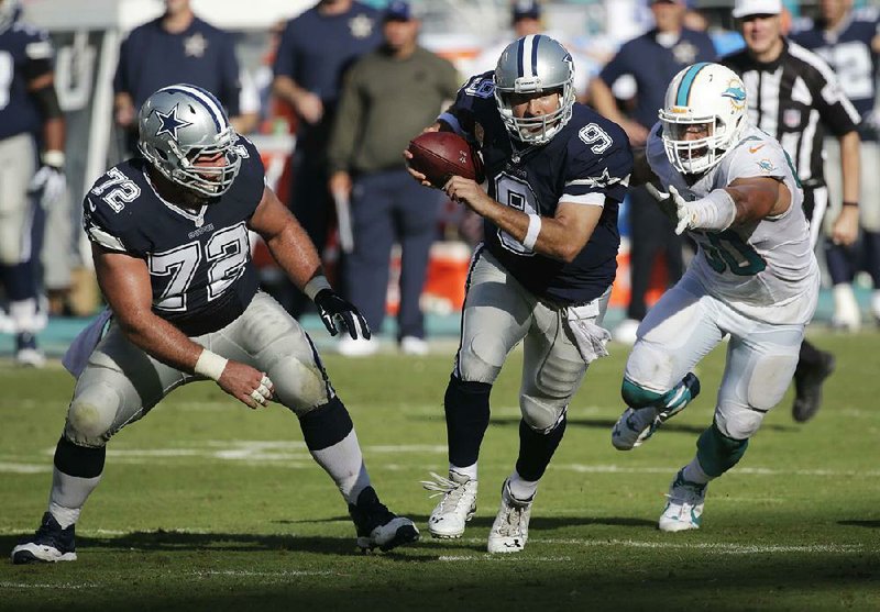 Dallas Cowboys quarterback Tony Romo (9) runs past Miami Dolphins defensive end Olivier Vernon (50) during the second half of Sunday’s game in Miami Gardens, Fla.