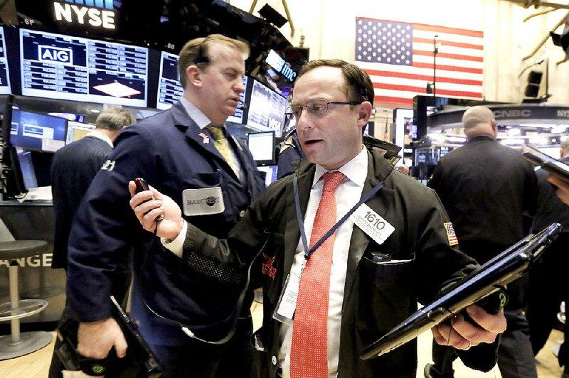 Trader George Baskinger (right) works Monday on the floor of the New York Stock Exchange.
