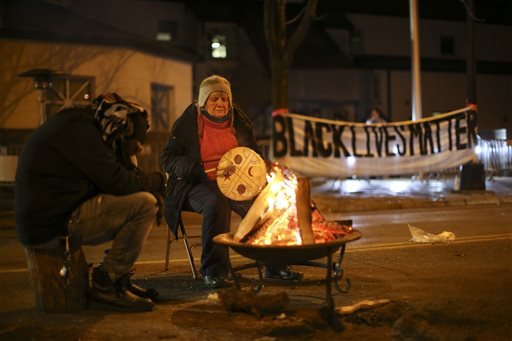 People warm themselves as they demonstrate about the Nov. 10 shooting of 24-year-old Jamar Clark in front of the Minneapolis Police 4th Precinct on Tuesday, Nov. 24, 2015.
