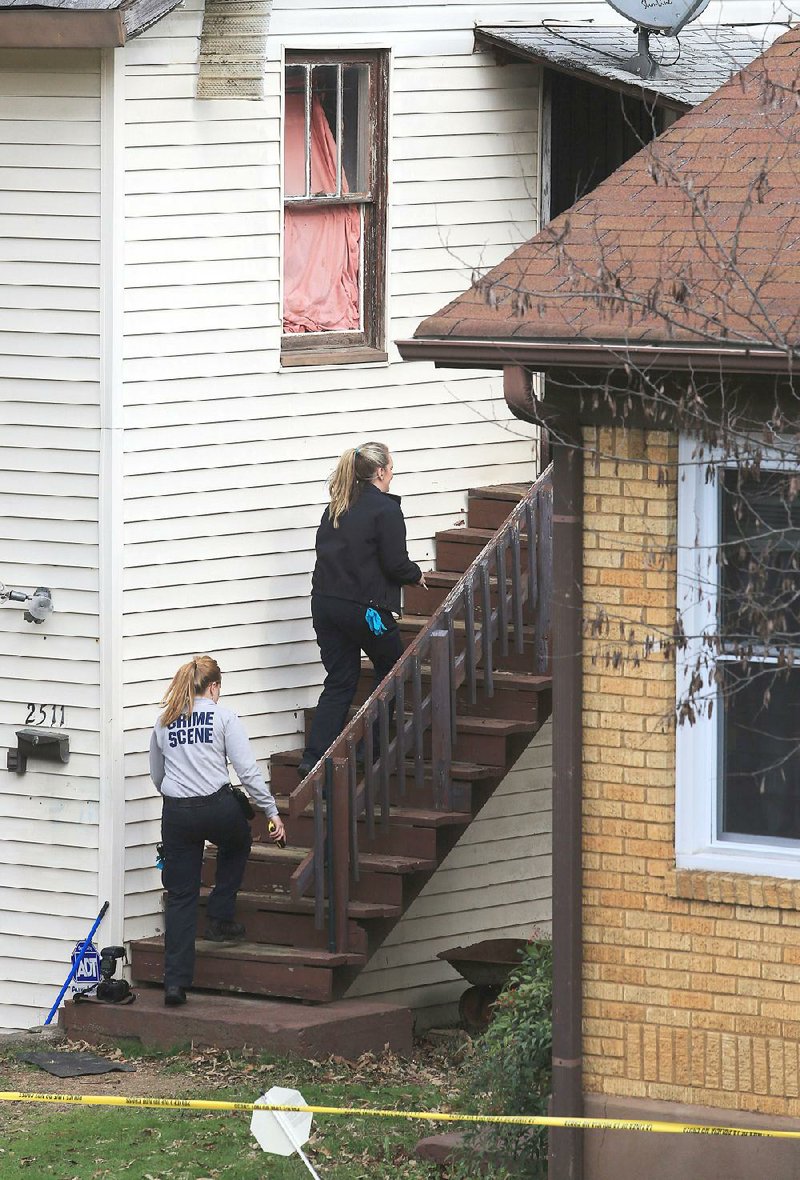 Little Rock crime-scene technicians head into a house in Little Rock on Tuesday where a woman had been found dead. 