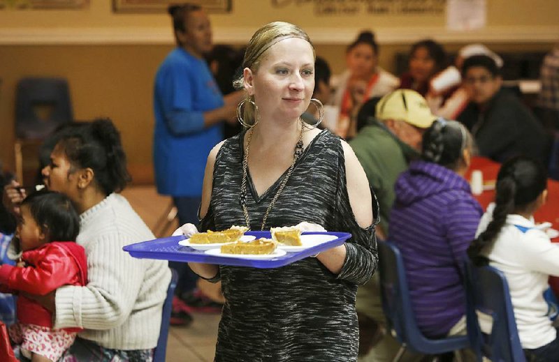 Wendi Campbell, with Tyson Foods Inc. Transportation, serves pumpkin pie Tuesday during the Samaritan Community Center’s annual Thanksgiving dinner in Springdale. Meals for 700 were served, with all of the food provided by a division of Wal-Mart Stores Inc. Some 500 bags filled with donated items from Wal-Mart for traditional Thanksgiving meals also were distributed.