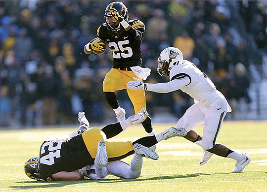 The Associated Press HURDLING: Iowa running back Akrum Wadley jumps over a Purdue defender being blocked by Hawkeye fullback Macon Plewa in the team's latest victory. The 11-0 Jayhawks, ranked No. 3 by The Associated Press, play at Nebraska on Friday before a Dec. 5 date in the Big Ten championship game.