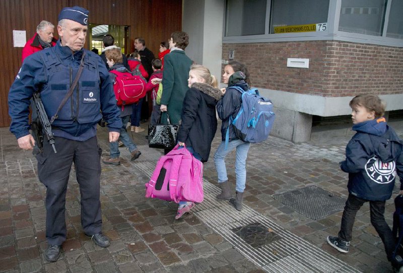 Under the eye of a heavily armed policeman, children arrive for school Wednesday in the center of Brussels after a four-day shutdown across the Belgian capital prompted by a threat alert. As investigators sought fresh leads in the manhunt for a key suspect in the Nov. 13 terror attacks in Paris, school officials sent out letters and emails to parents explaining heightened security measures for their children. 