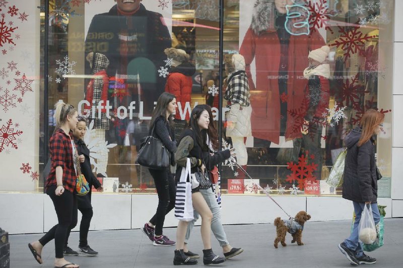 Shoppers pass a Christmas display in a store window in San Francisco on Sunday. Consumers spent a little bit more in October than in September and incomes rose 0.4 percent, the Commerce Department said Wednesday. 
