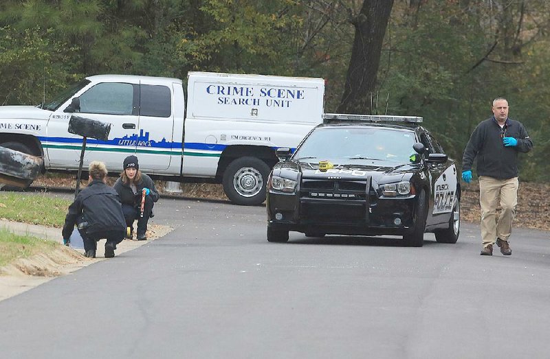 Little Rock police crime scene technicians (left) and a detective investigate the scene of the apparent murder of a man at West 38th and Zion streets in Little Rock on Wednesday. A man was found early Wednesday sitting in the driver seat of a car with the left rear passenger window shot out.