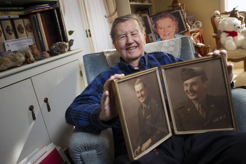 Hugh Montgomery, 91, a former CIA and OSS officer who parachuted into Normandy on D-Day with the 82nd Airborne., holds two photographs of himself in 1943, at his McLean, Va., home, Tuesday, Nov. 24, 2015. 