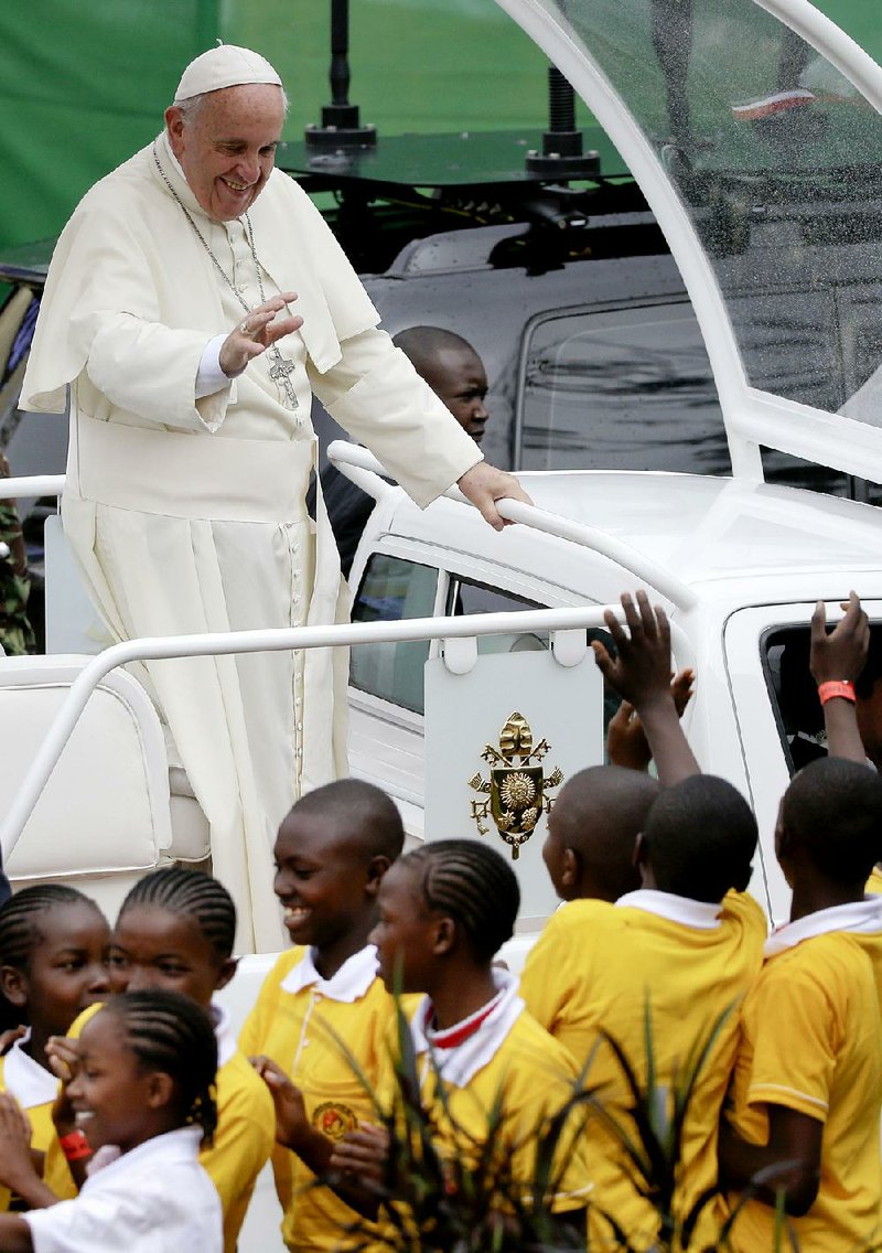 Pope Francis waves to children as he arrives Thursday to celebrate a Mass on the campus of the University of Nairobi in Kenya. 